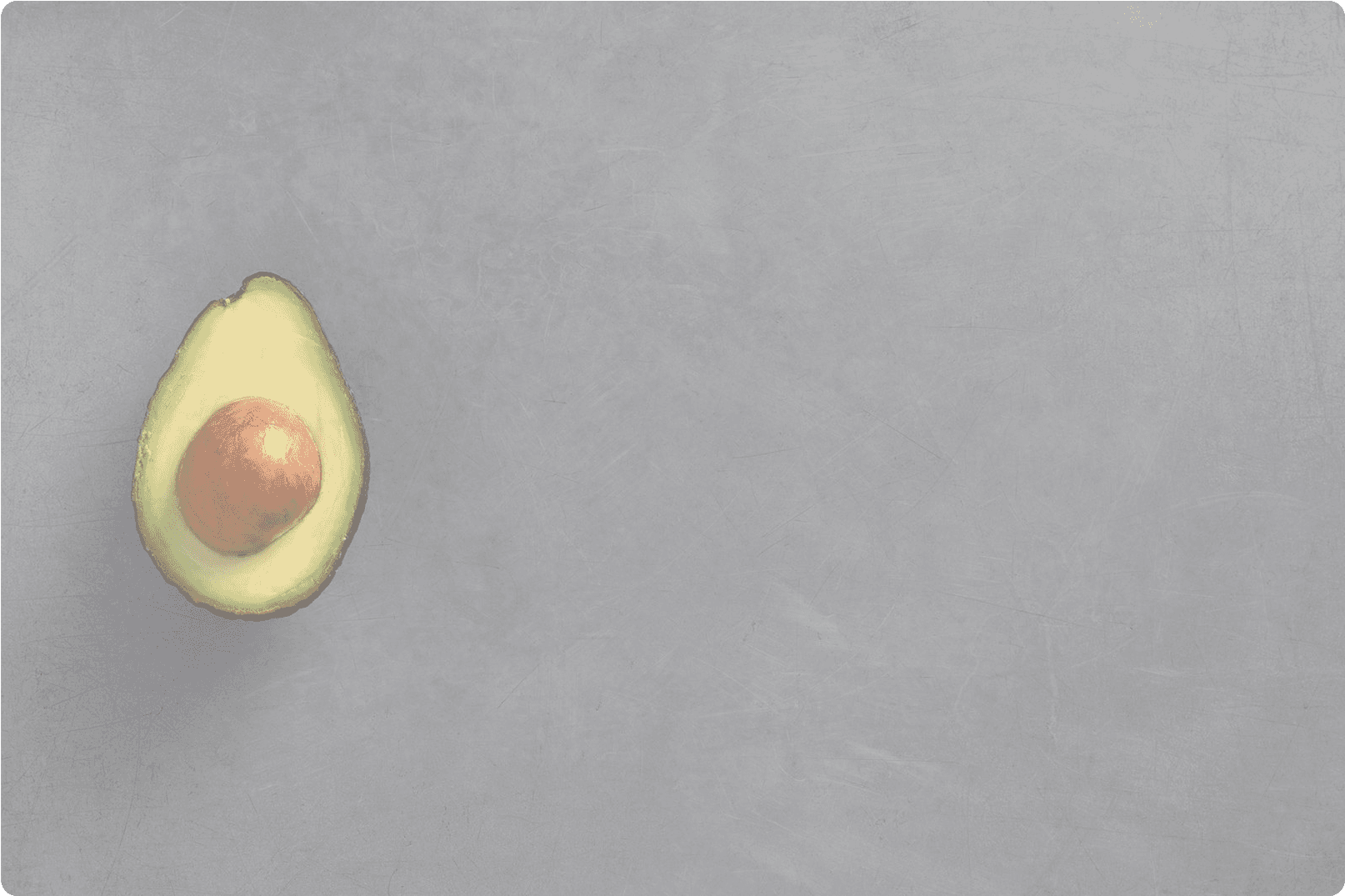 Half a Hass avocado on a grey stone surface